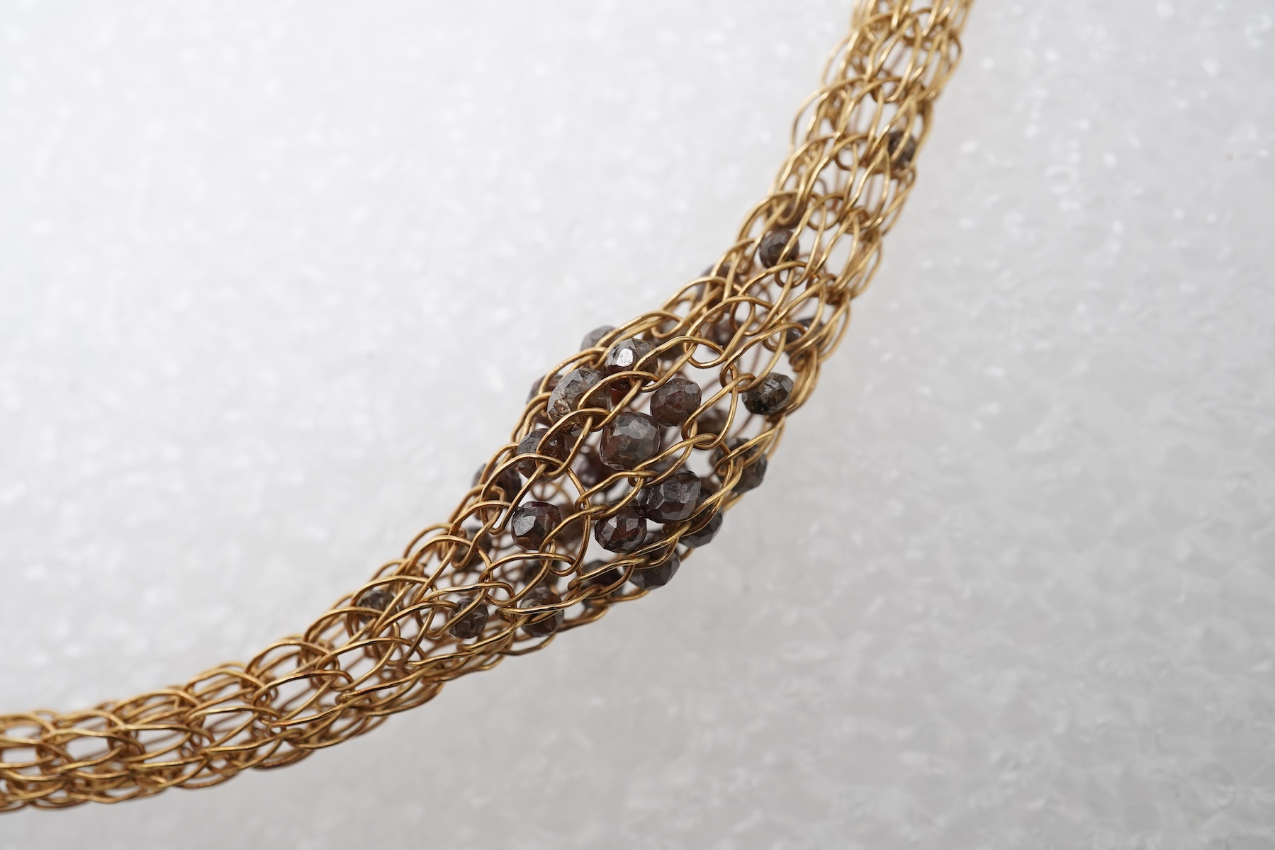 An 18ct gold and diamond necklace, composed of a woven tube of 18ct gold wire links, three sections threaded with brown diamond beads, length approximately 45cm, British hallmarks, sponsor's mark TJH, gross weight approx
